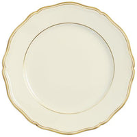 A Mazurka Gold & Ivory dinnerware plate by Raynaud features a cream color, scalloped edge, and thin gold trim, exemplifying French craftsmanship, set against a white background.