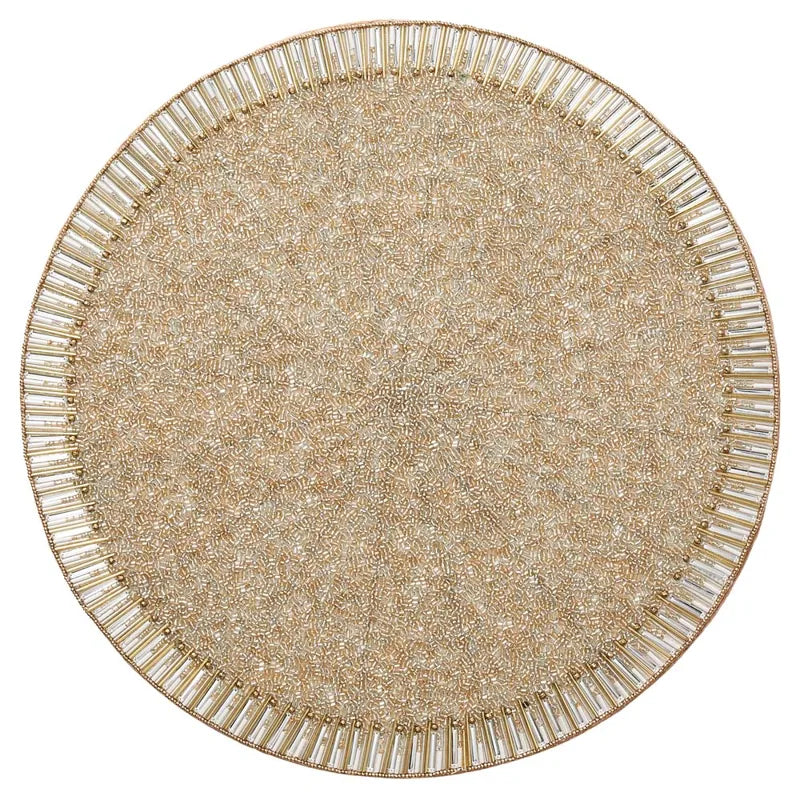 The Bevel Placemat Set of 4 by Kim Seybert features round, gold-toned beaded placemats with an intricate design and clear bead accents along the outer edge, offering a sophisticated and decorative touch to elevate any formal table setting.