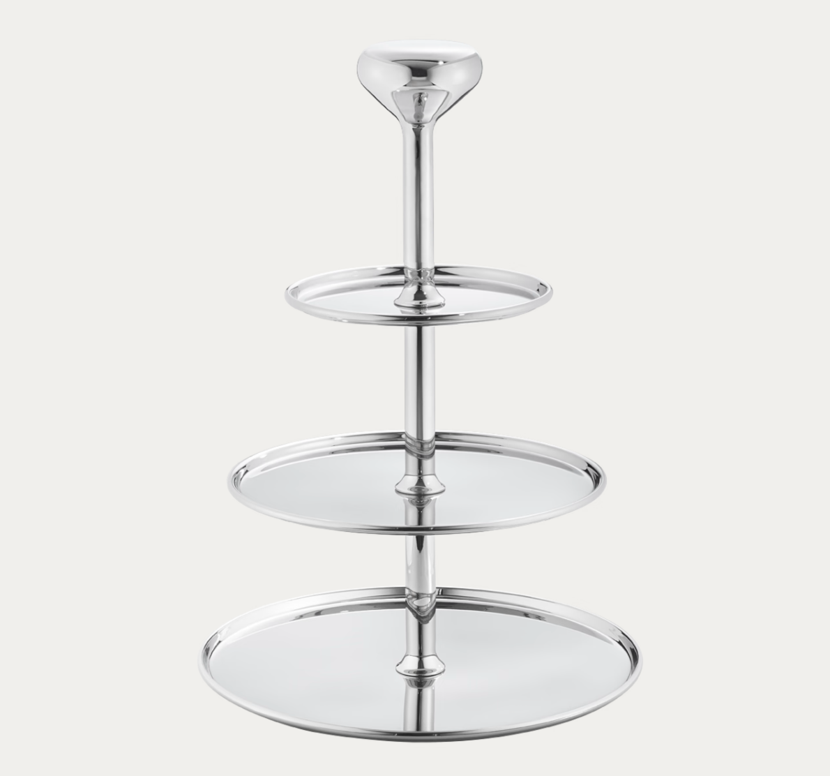 The Alfredo Ètagère by Georg Jensen is a polished silver, three-tiered serving tray with a central vertical stand and round trays that increase in size from top to bottom, presented against a plain white background.