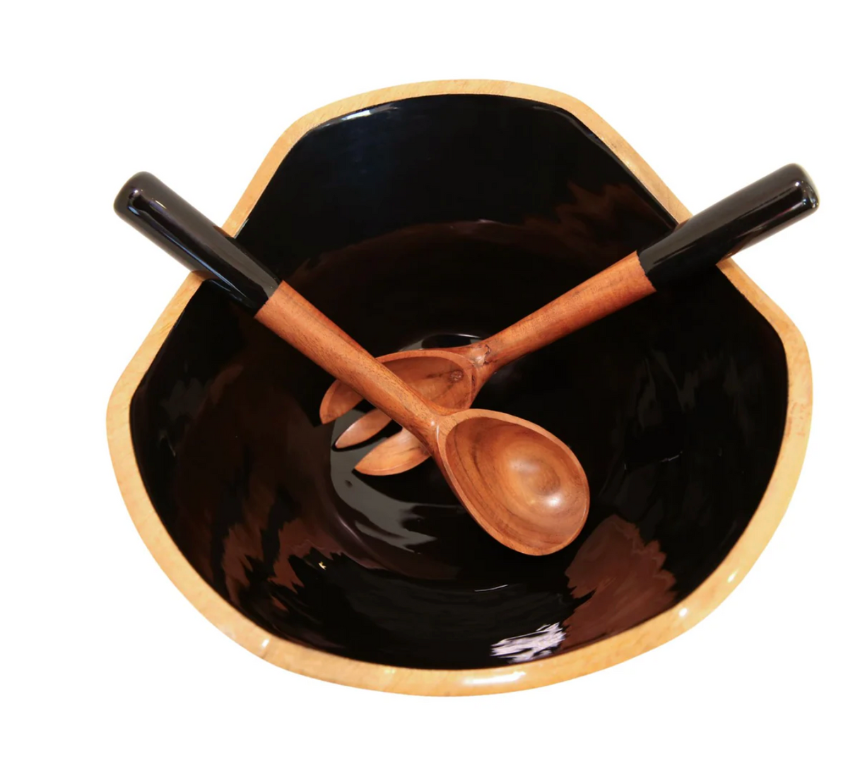 The Montauk Serving Bowl With Servers by Indy Home is a black, irregular mango wood bowl with a natural rim, holding a handmade fork and spoon with black handles, crossed in an X shape.