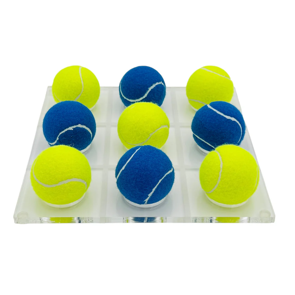 The Tennis Ball Tic Tac Toe - Blue / Yellow by Luxe Dominoes features a 3x3 clear acrylic board with blue and yellow tennis balls—a unique coffee table game and perfect gift for tennis fans.