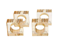 Four amber-hued, square-shaped lucite napkin rings from the BT- Shalom Lucite Cube Napkin Ring Set of 4 are arranged in pairs on a white background, showcasing contemporary table decor.