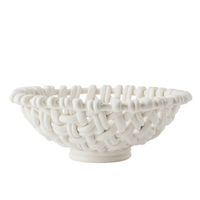 The Skyros Woven Basket - Round-15" is a white ceramic bowl inspired by handwoven baskets, crafted by Portuguese artisans with open loops and a smooth, matte finish for an airy look.