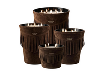 Four brown suede-covered Calamity Jane Candle - Deadwood candles with fringe detailing, each lit with multiple flames.