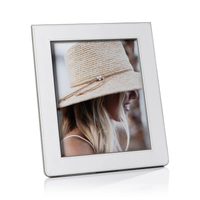 The Zodax Napoli Leather Frame White & Grey displays a portrait of a woman in a straw hat, her face partly hidden as she looks down and to the side. The frame stands angled on a white background.