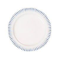 The Sitio Stripe Dinnerware by Juliska is a round white dinner plate with a scalloped edge, whitewash glaze, and evenly spaced short Delft blue lines along the rim.