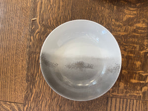 The Marie Daâge Maarie Daâge Horizon Platinum Dinnerware, a hand-painted white ceramic bowl with a gray gradient, made in France, rests on a natural wood grain surface.