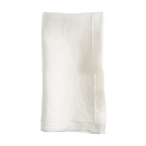 The Saro Trading Overlock Stonewash Border Napkin, a plain white cloth napkin with subtly frayed edges for a classic touch, is displayed neatly folded against a white background.