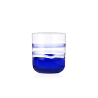 The Gesti Tumbler by Ichendorf Milano features clear glass with a striking blue gradient at the base that gradually transitions to transparent at the top, showcased against a plain white background.