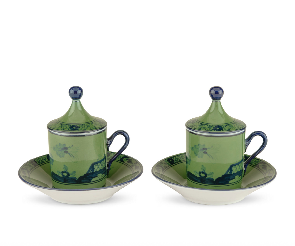 Two lidded Ginori 1735 Oriente Italiano Malachite teacups with blue handles, each sitting on a matching saucer featuring dark blue and green floral patterns.