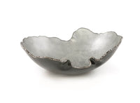 The Gardeco Mapa Grey & Silver Trim Bowl features a sculpted metallic design with an uneven, wavy rim and a textured silver-gray surface, reminiscent of artisan glassware, presented against a white background.