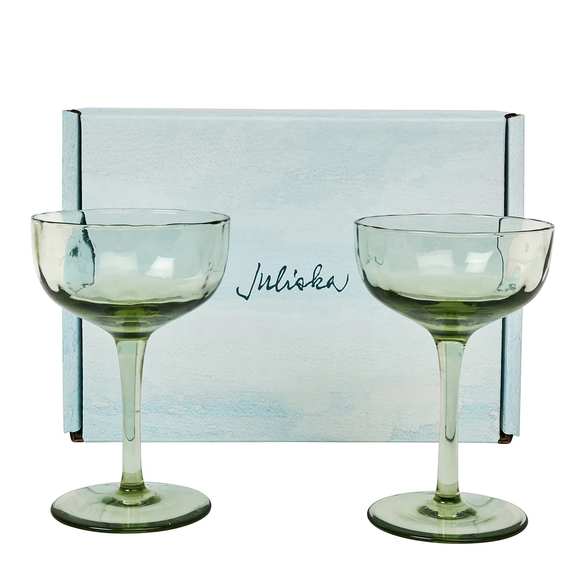 Two light green Juliska Puro Cocktail Coupes (set of 2) are displayed in front of a light blue, gift-boxed set featuring the brand’s elegant cursive logo—perfect for serving stylish cocktails.