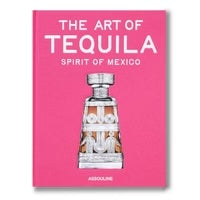 Assouline’s The Art of Tequila, a hardcover book with a bright pink cover featuring a central image of a glass tequila decanter and the text The Art of Tequila, Spirit of Mexico.