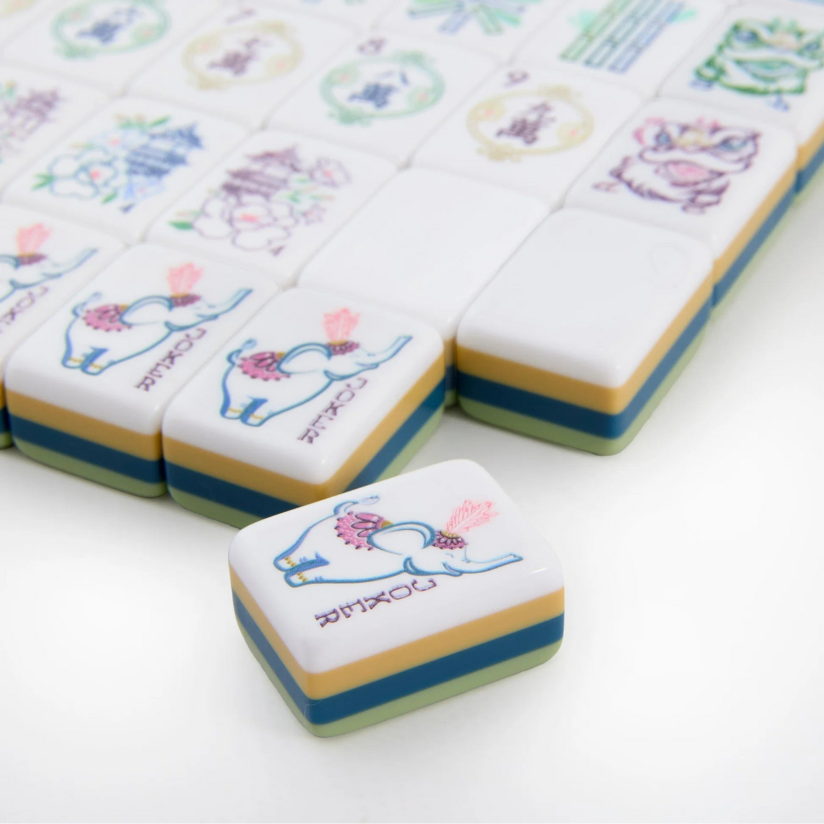 A set of vibrant Willow Mahjong Tiles from Oh My Mahjong features an elephant illustration on the visible pieces. One tile from the elegant Mahjong Tiles Set - Willow is separated and placed prominently in the foreground.