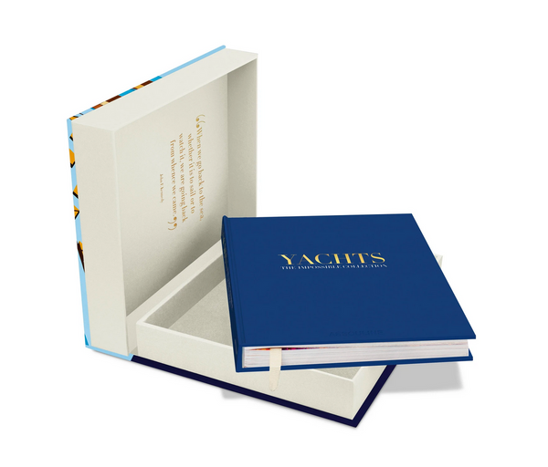 Assouline’s Yachts - Impossible Collection, a luxurious blue hardcover book, sits partially open in an elegant matching presentation box featuring a gold inscription inside the lid.