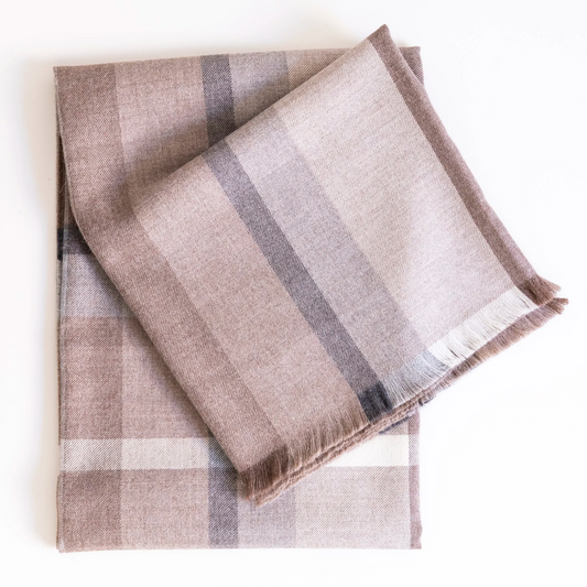 The Dove & Donkey Bolsa Throw is a folded beige and brown modern plaid blanket with fringed edges, displayed on a white background.