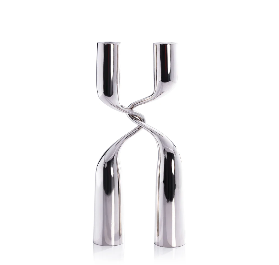 The Zodax Interlock Candle Holder in polished nickel features two twisted stems forming an X-like design, ideal for modern décor and shown elegantly against a white background.