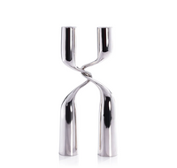The Zodax Interlock Candle Holder in polished nickel features two twisted stems forming an X-like design, ideal for modern décor and shown elegantly against a white background.