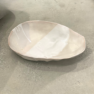 The Ripple Oval Large Bowl by Alex Marshall Studios is a handmade ceramic piece with an irregular shape and glossy off-white finish, ideal as an oversized serving bowl for salads.