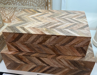 Two rectangular Bojay Modular Box pieces, handcrafted with geometric herringbone patterns in brown tones, are stacked to display artisanal craftsmanship. Decorative carvings and other items are visible in the background.