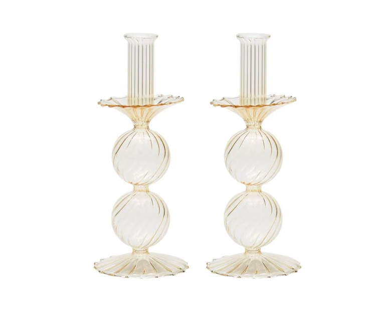 The Bella Candlestick Holder Set of 2 by Kim Seybert showcases two elegant candlestick holders crafted from hand-blown glass, featuring ribbed, spherical shapes stacked vertically and a fluted base, displayed against a plain white background.