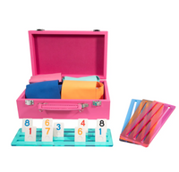 A bright pink Mini Travel Rumi Set by Brouk & Co, featuring colorful cloths, numbered game tiles on a blue rack, and four colorful tile holders—ideal for pairing with your travel backgammon set.