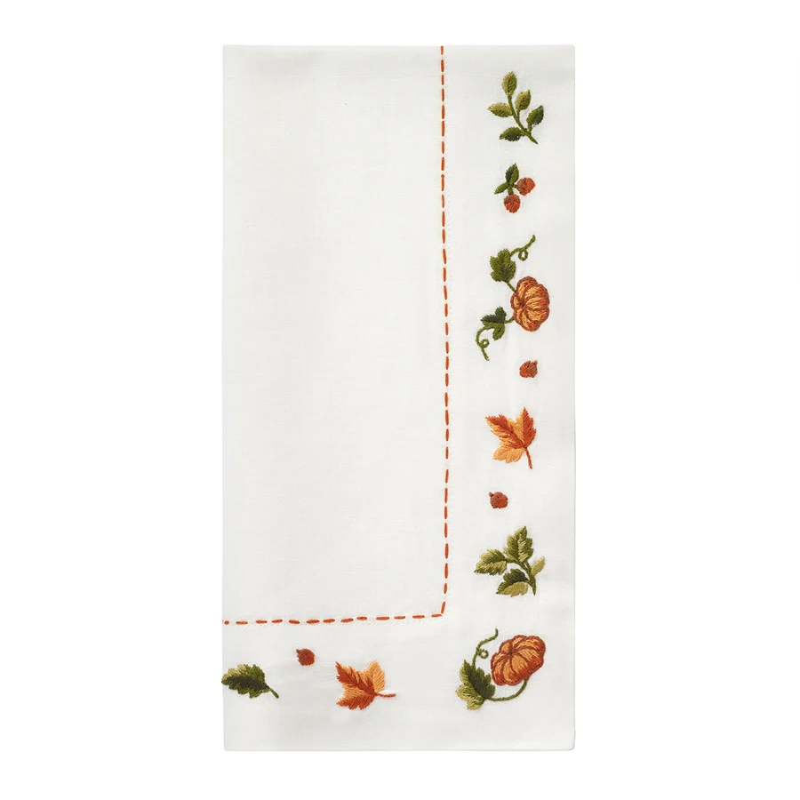 Add a festive touch to your table with the Bodrum Autumn Medley Napkin Set of 4—white cloth napkins featuring embroidered orange pumpkins, autumn leaves, green vines, and a decorative orange stitched border along two edges. Perfect for Thanksgiving entertaining or pairing with coordinating fall napkins and embroidered table runners.