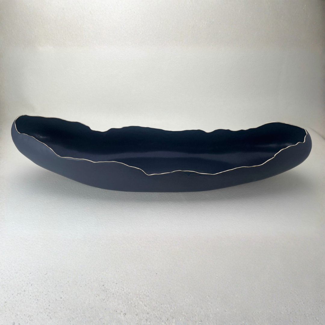 The Long Boat Bowl #1 - Black by Kate Tremel is a long, narrow black ceramic bowl featuring uneven, wavy edges outlined in white, displayed on a plain light background—perfect as a striking centerpiece or a unique serving bowl.