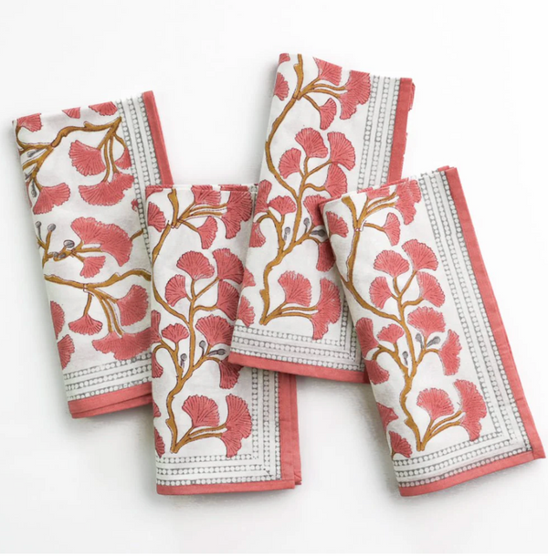 The Pomegranate Ginkgo Napkin Set of 4 – Coral features white cloth napkins with a pink and gold ginkgo print and a pink border, making a charming addition to your table decor.