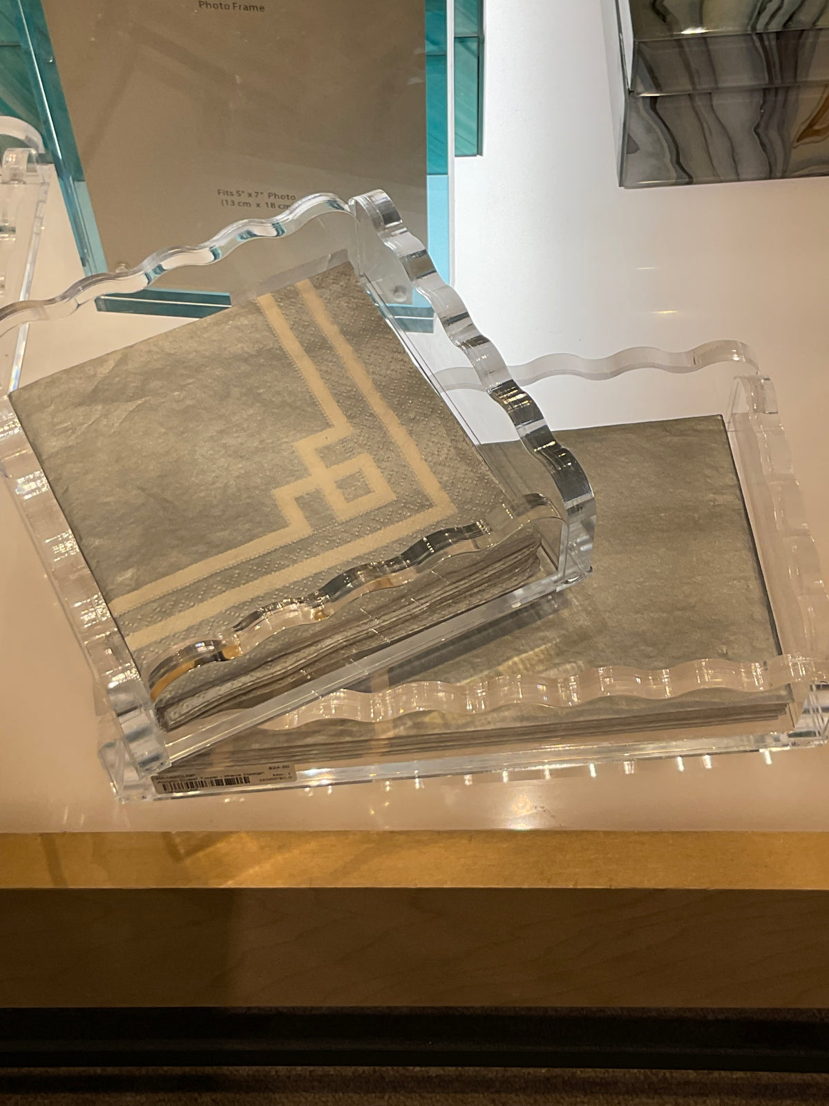 Tizo Waverly Guest Towel Holder: a clear, scalloped-edge acrylic holder containing a stack of grey and white patterned paper guest towels.