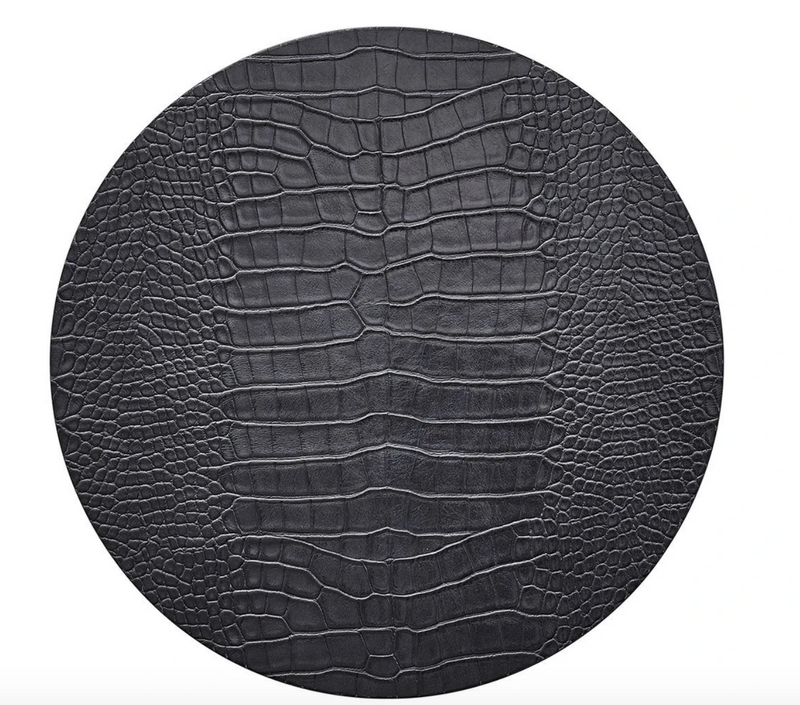 The Kim Seybert Croco Placemat Charcoal Set of 4 features a round, black surface with a textured, crocodile-embossed pattern resembling reptile skin, showcased against a white background.