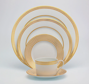 The Latitudes Dinnerware by Royal Limoges features fine porcelain with gold concentric circles, including four plates of various sizes and a teacup with matching saucer, all displayed neatly against a white background.
