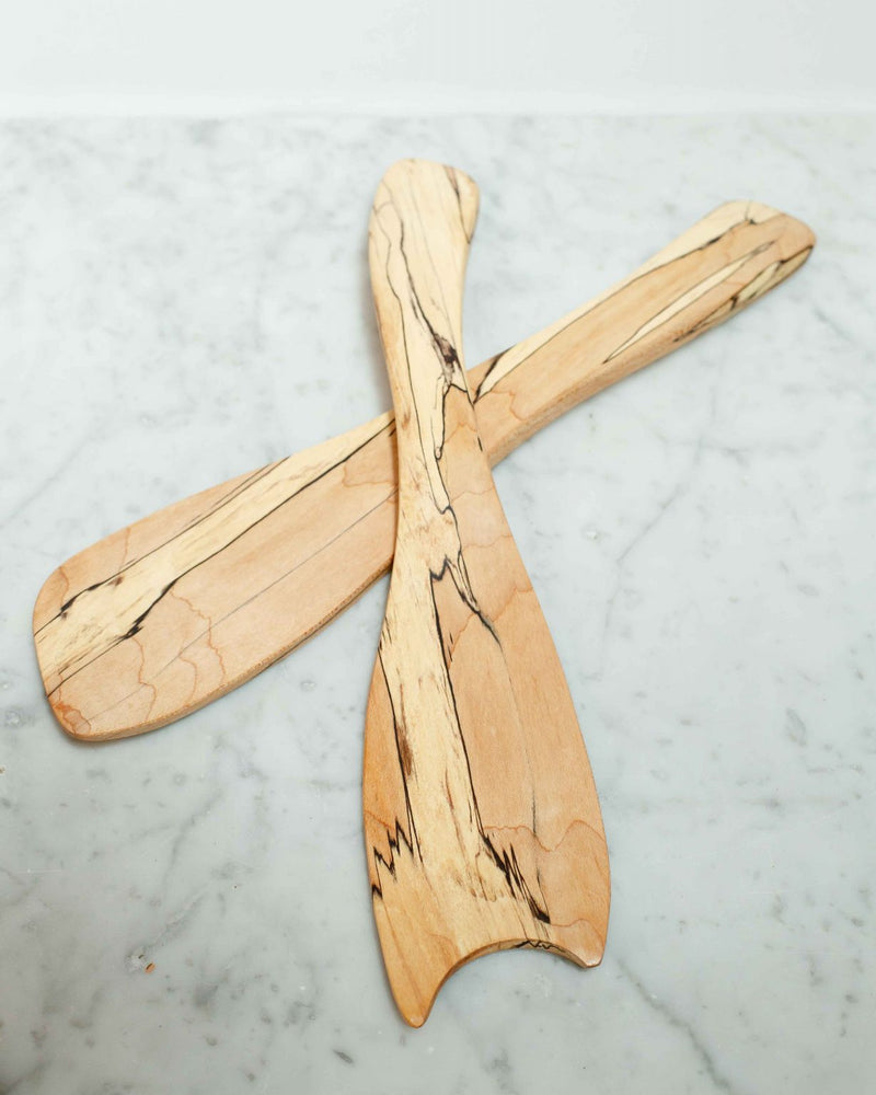 Two Spalted Maple Rustic Salad Tossers by Peterman, featuring dark grain patterns, are crossed on a white marble surface.