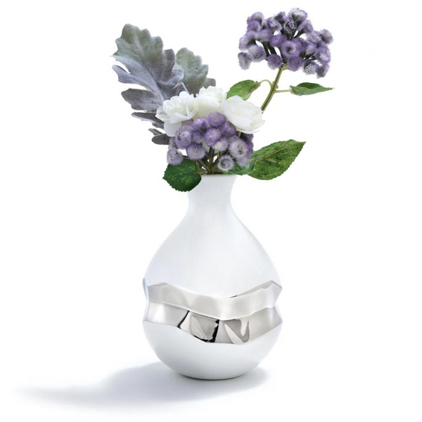 The silver bud vase has a silver painted 3D geometric shape at the center. Vase is made of white ceramic and has purple flowers.